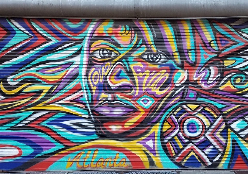 Atlanta security gate mural with a large patterned face and hand-lettered Atlanta script