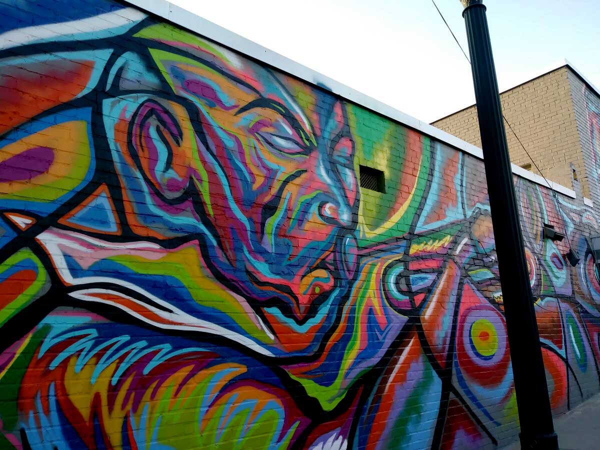Street mural of an oversized face in rainbow colors on a painted brick wall in Atlanta