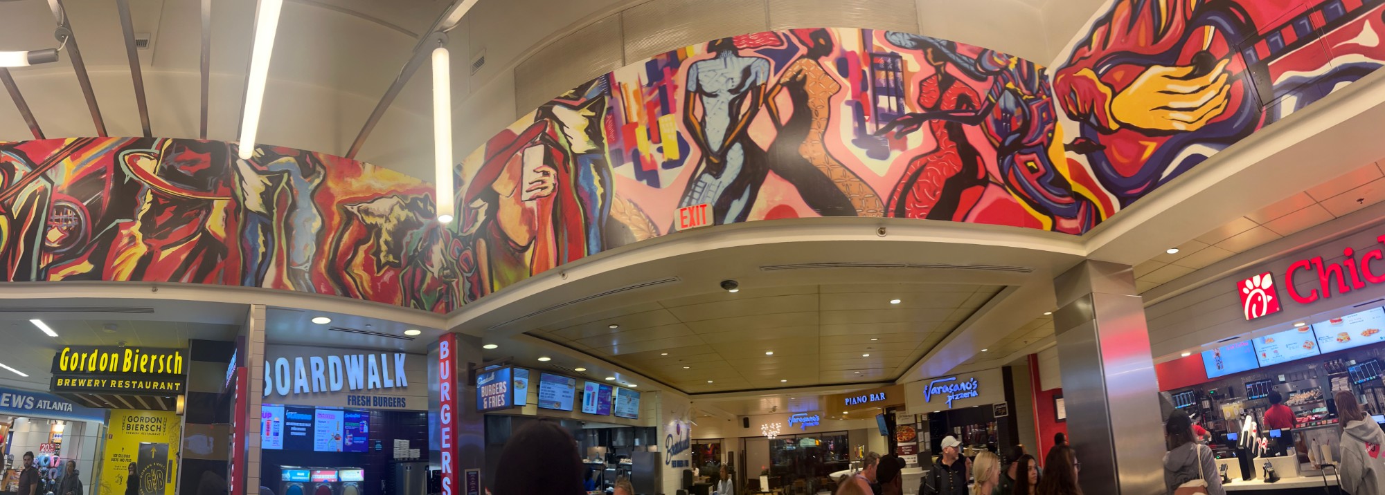 Panoramic airport atrium mural of musicians and dancers above concourse restaurants in Atlanta