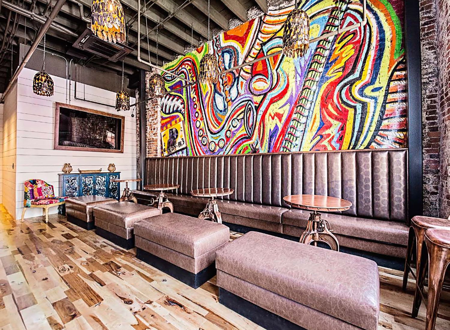 Colorful abstract jazz mural painted on exposed brick above banquette seating in an Atlanta restaurant interior