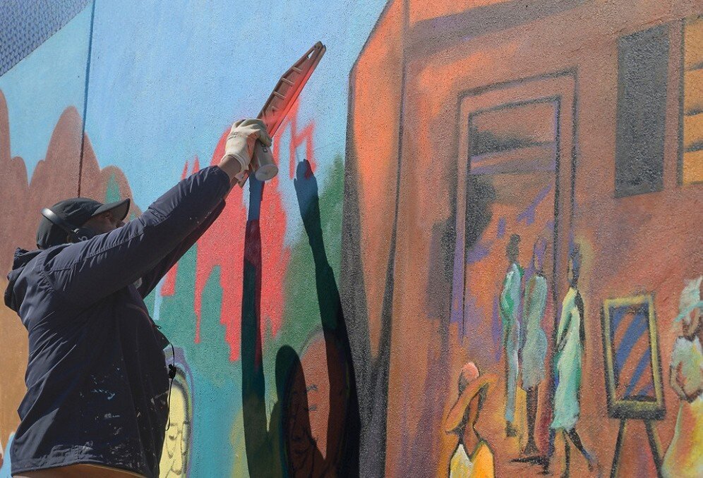 Corey Barksdale spray-painting detail on the barbershop scene panel of the Blandtown mural