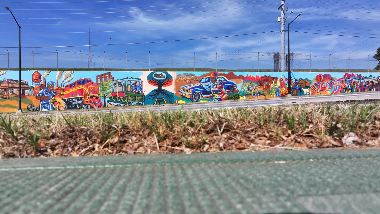 Ground-level street view of the completed Blandtown mural along Northside Drive under a clear Atlanta sky