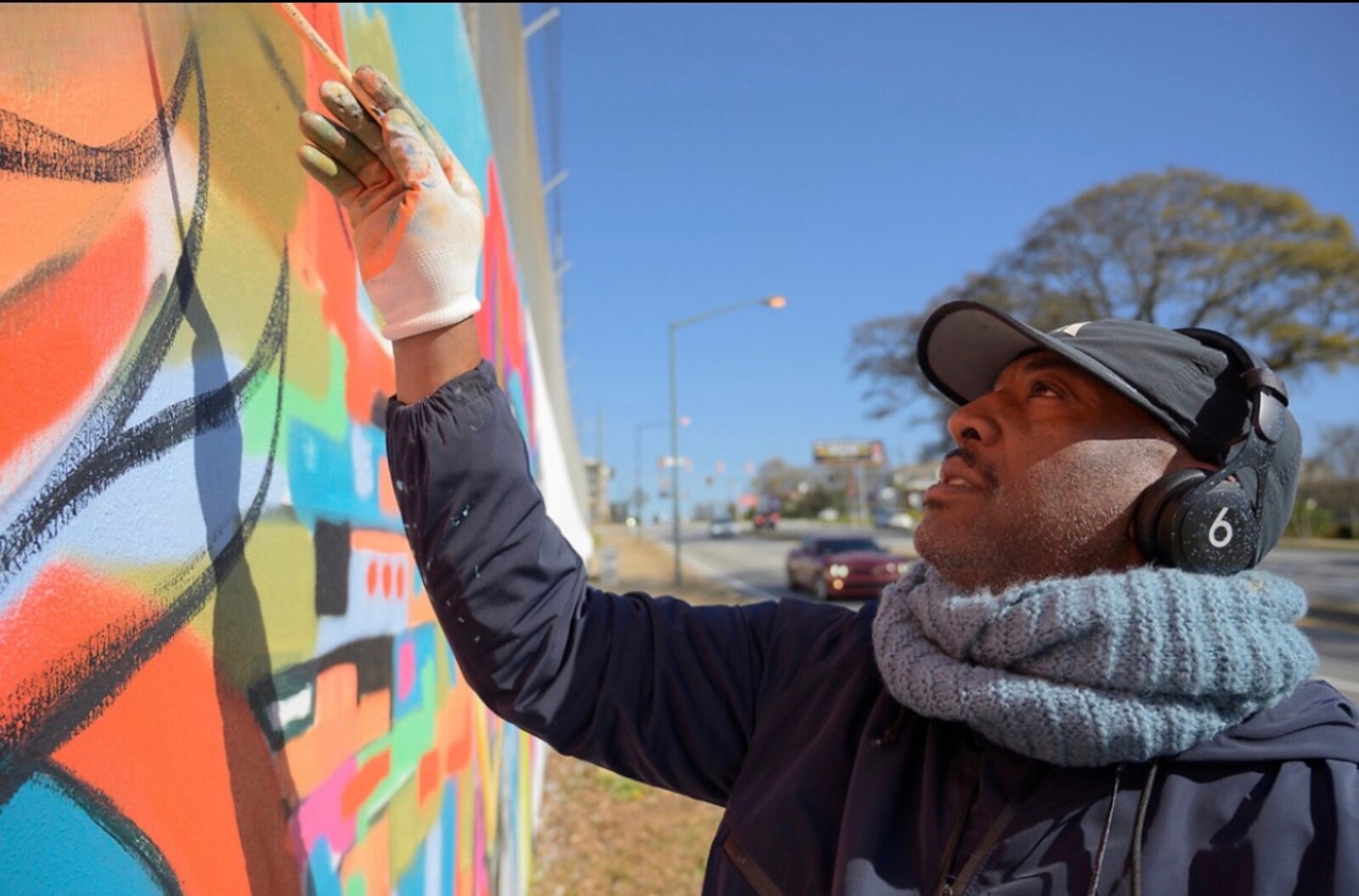 Close-up of Corey Barksdale painting a detail panel of the Blandtown mural on Northside Drive