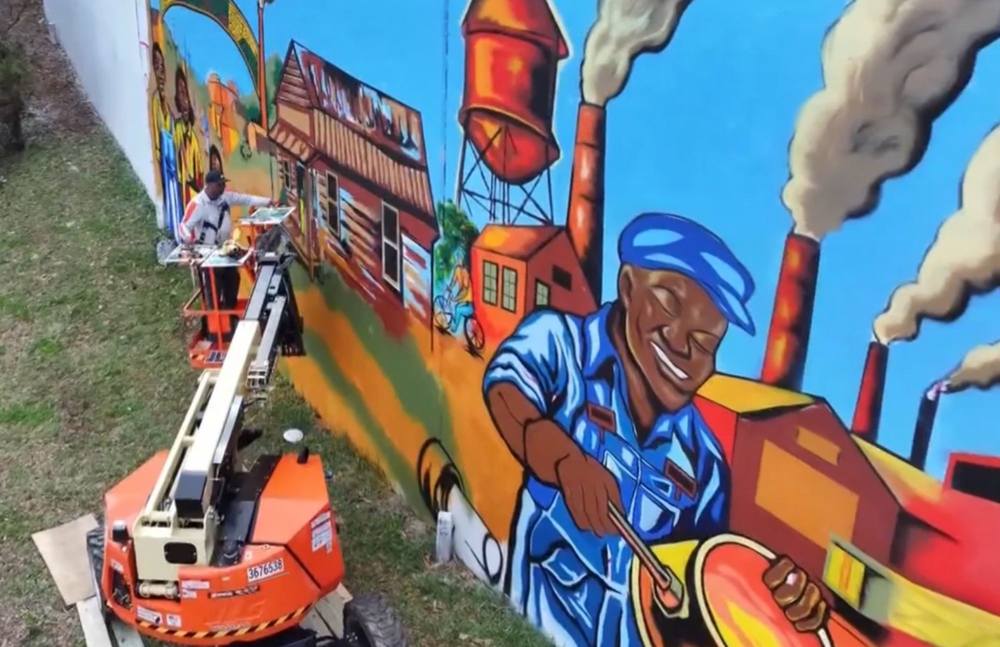 Aerial view of Atlanta muralist Corey Barksdale painting the Blandtown mural from a boom lift on Northside Drive