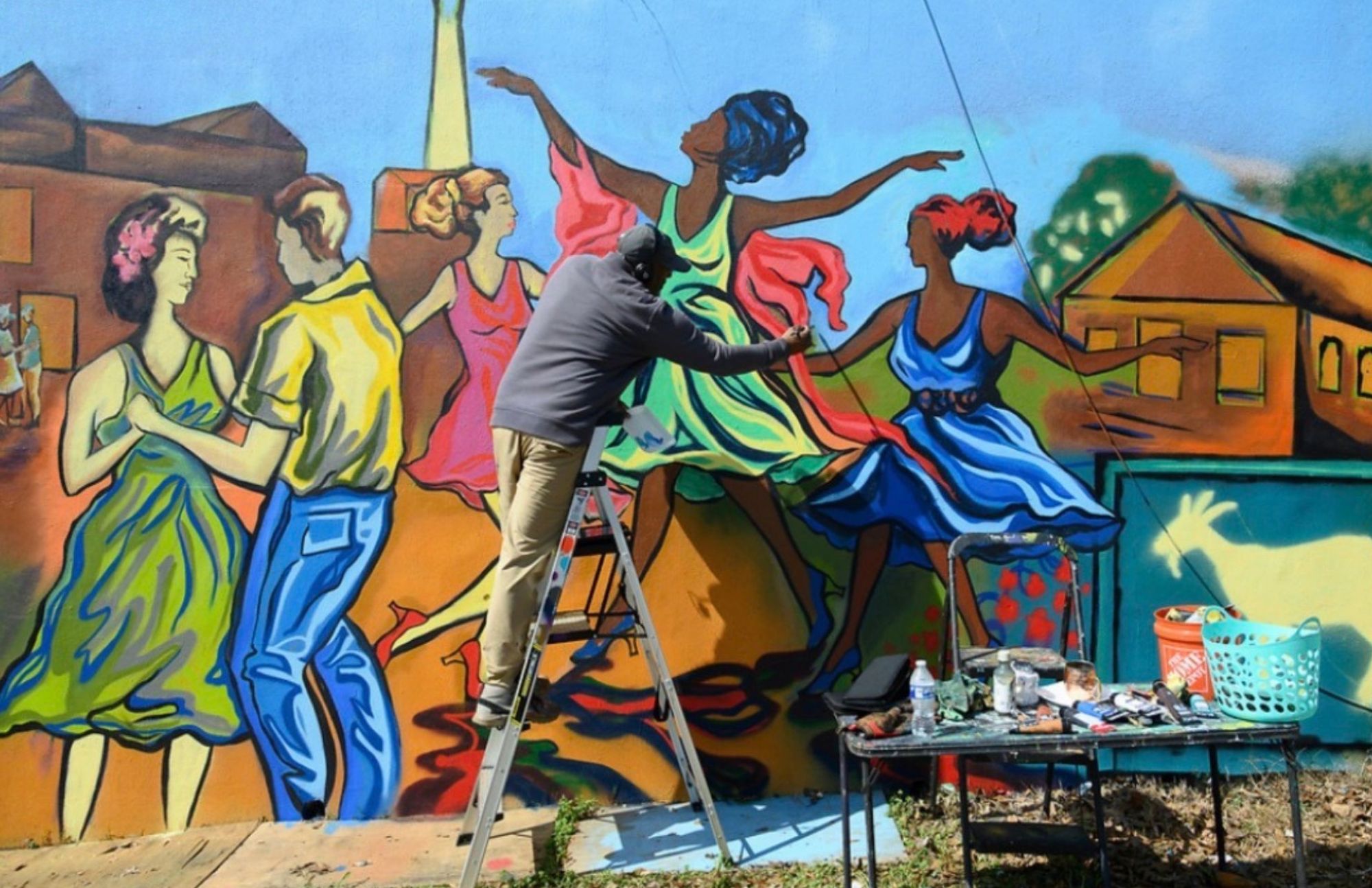 Corey Barksdale hand-painting a mid-century dance hall scene on the Blandtown mural