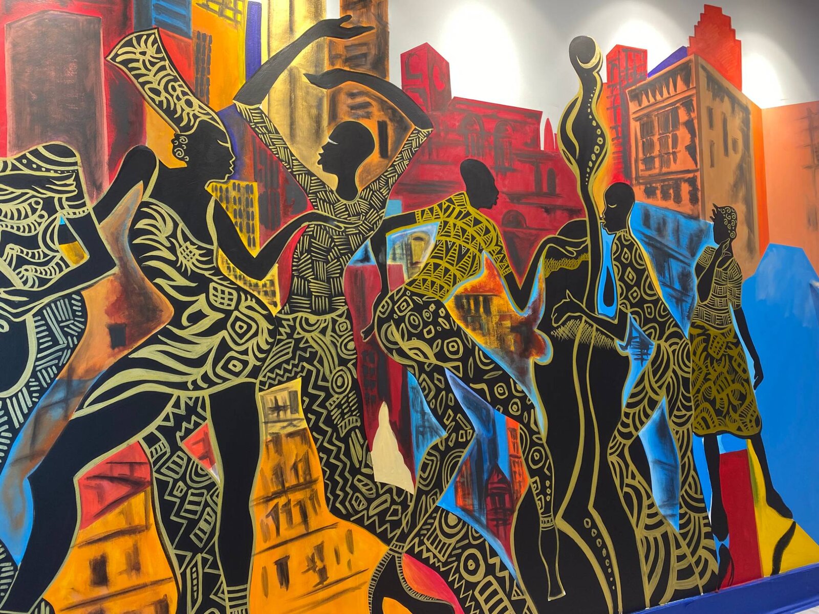 Close-up detail of silhouetted dancers and a saxophonist in African-pattern textiles from the Decatur East mural