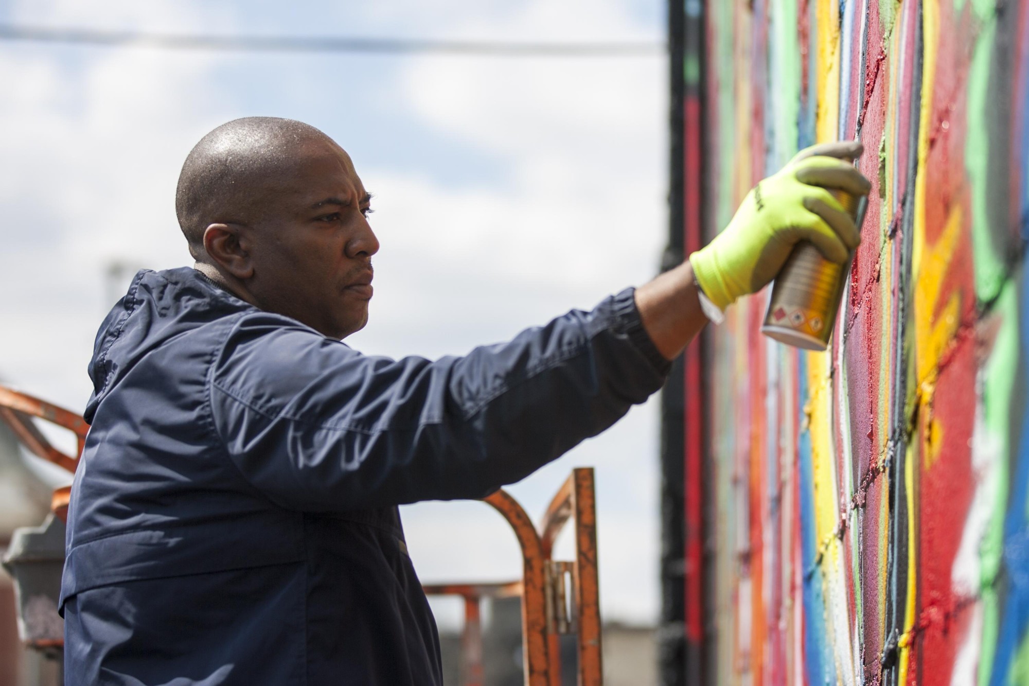 Corey Barksdale painting the CRE8IV mural in Rockford, Illinois with a spray can