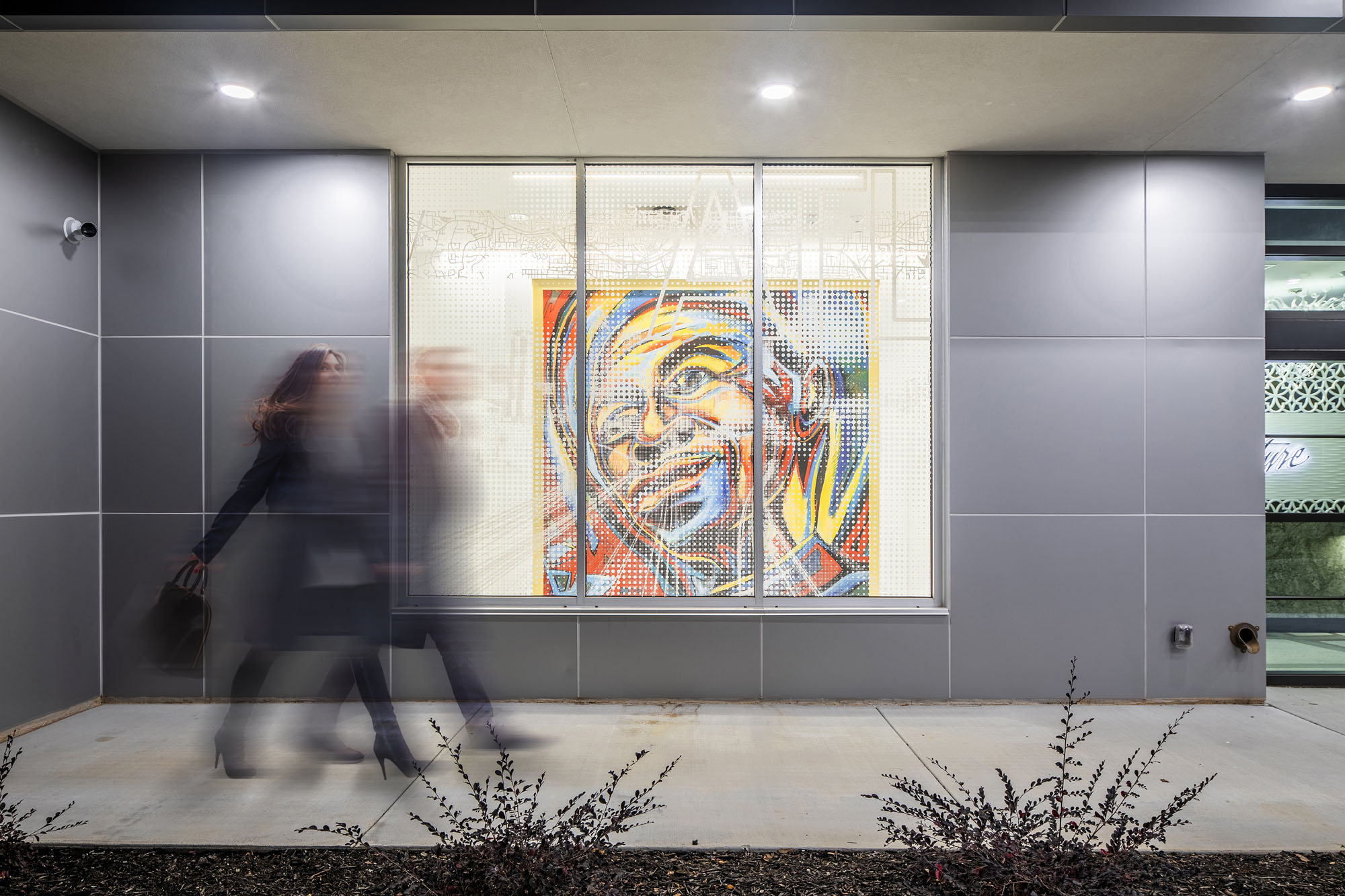 Window-mounted portrait mural at the Signature Aviation Executive Terminal entrance, lit at night