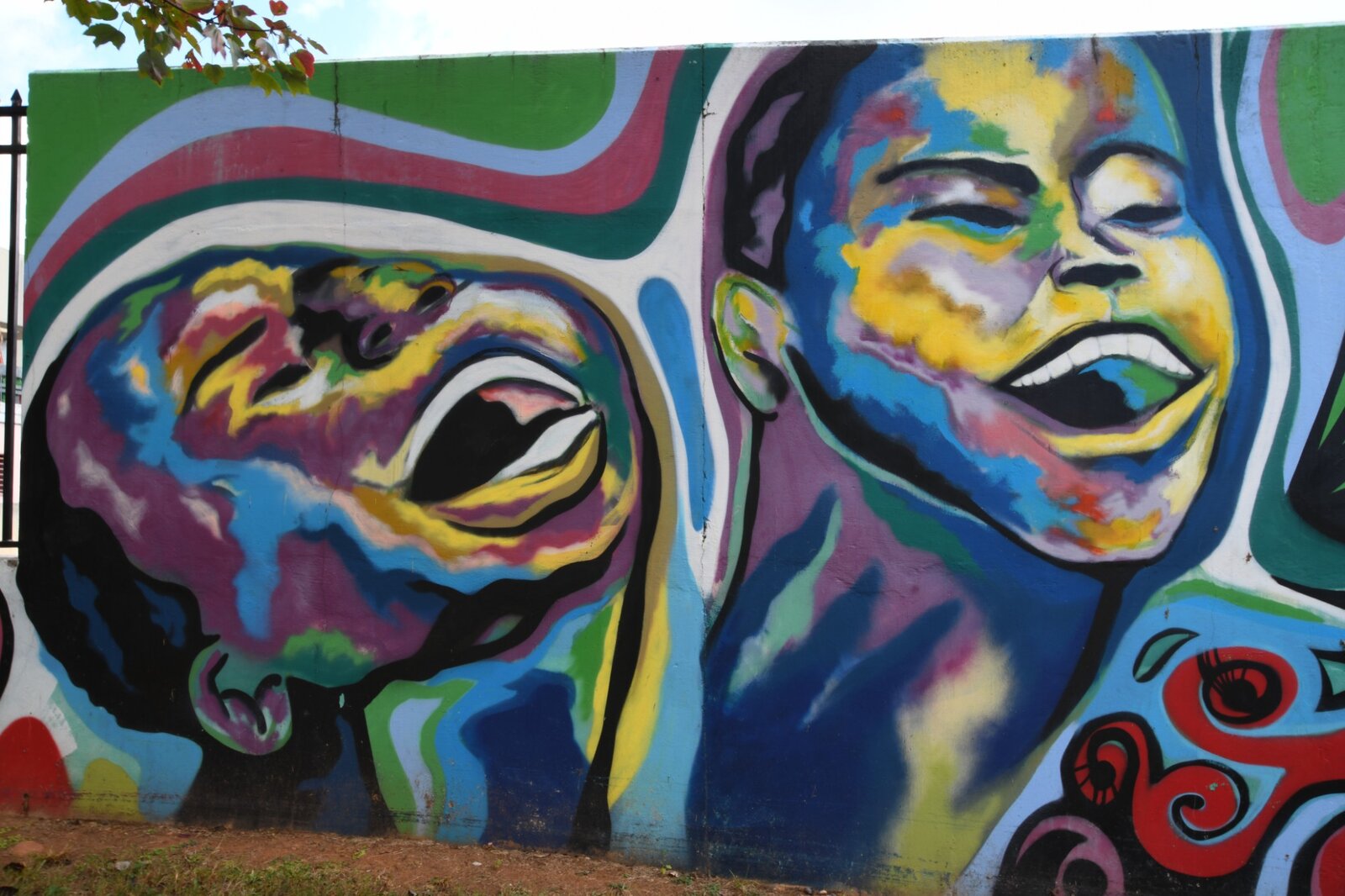 Two laughing faces in vibrant abstract color, Pittman Park mural by Atlanta mural painter Corey Barksdale